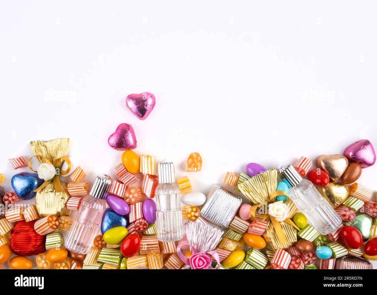 Top view half full various sweet assortment. Isolated white background, copy space. Candy, wrapped chocolate, hearth shape, almond, cologne mixed. Stock Photo