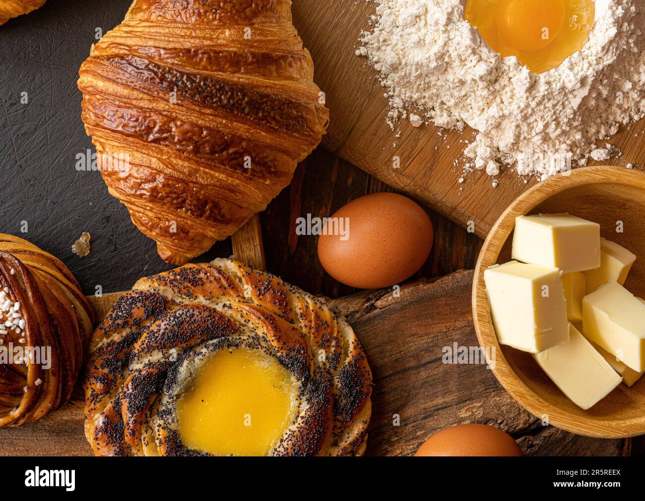Freshly baked Swedish cinnamon bun, croissants and cream spandauer, butter, eggs and flour Stock Photo