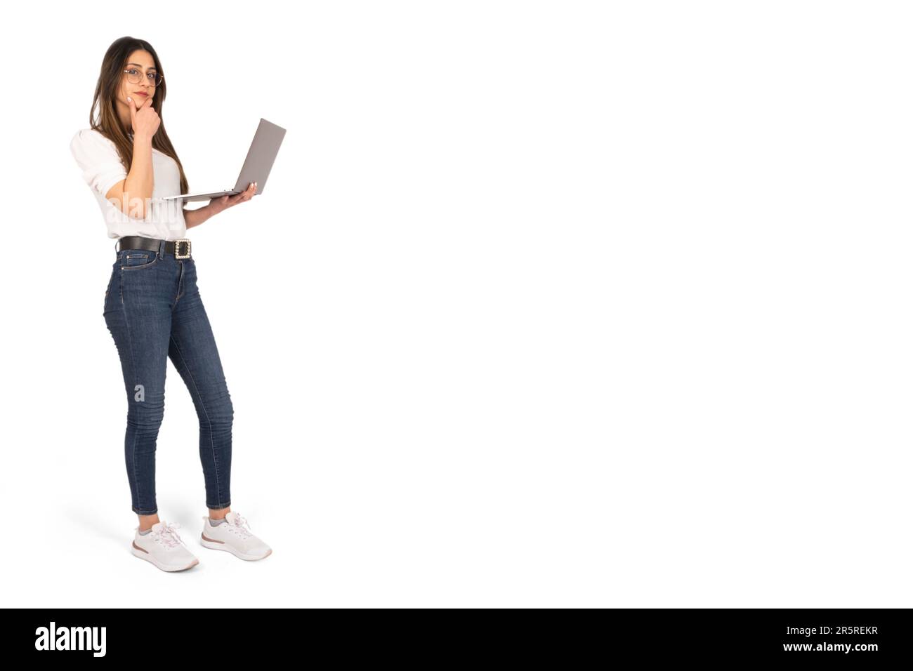 Full body view young business woman stand over isolated white studio background. Holding laptop. Thinking, thoughtful office worker hand off chin. Stock Photo