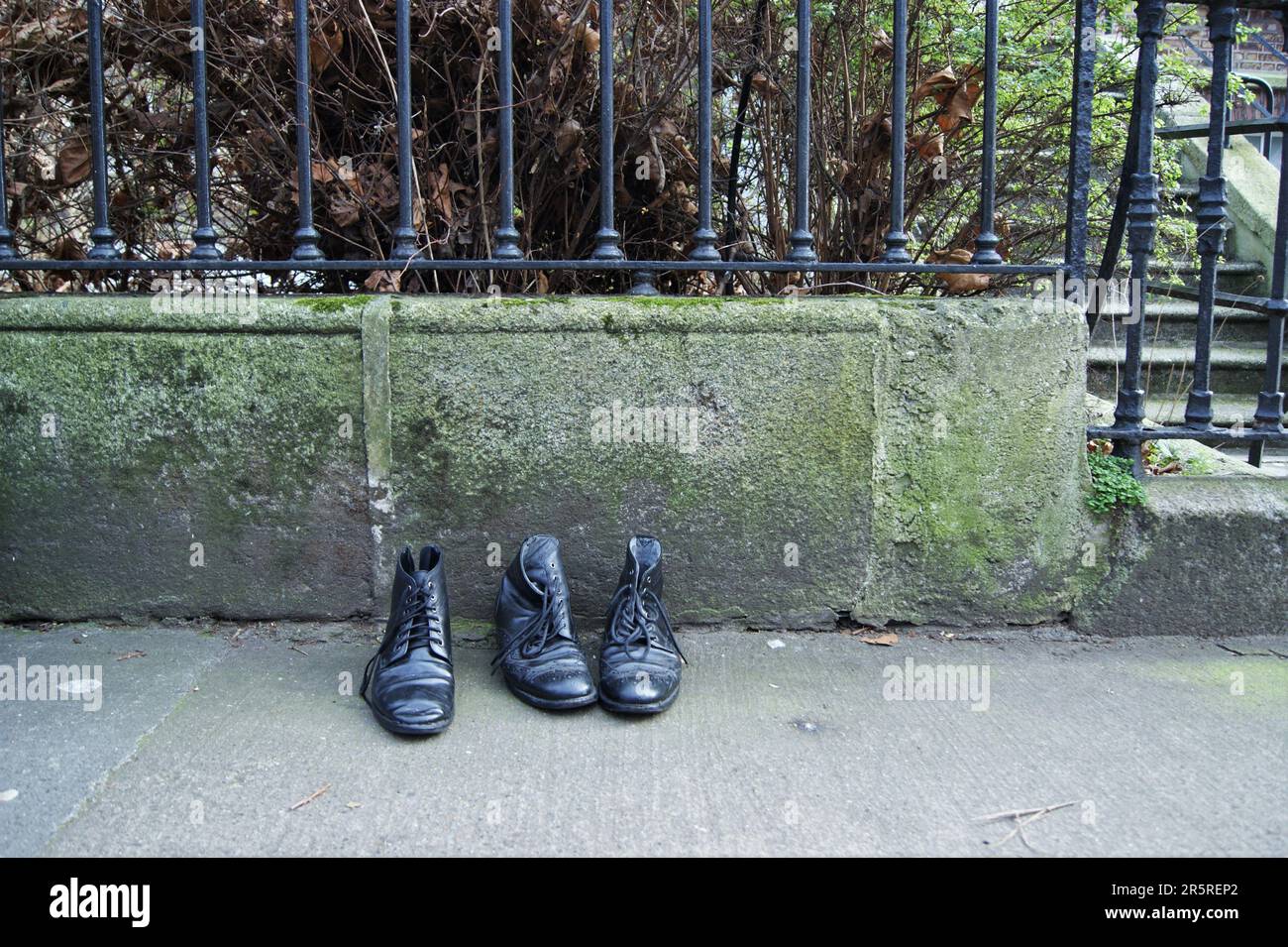 Black men's shoes. Old black men's shoes by an old fence. Stock Photo