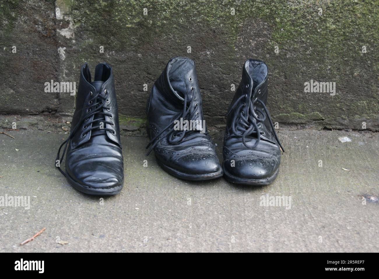 Old black leather shoes on the street. Black men's shoes. Stock Photo