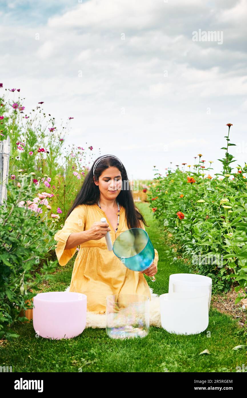 Woman playing music on crystal singing bowls, relaxing in beautiful green garden Stock Photo Alamy