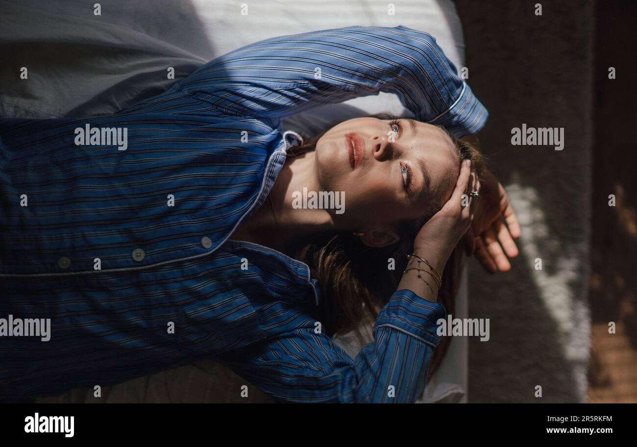 Top view of woman lying in her bed, morning sun shining on her face. Stock Photo