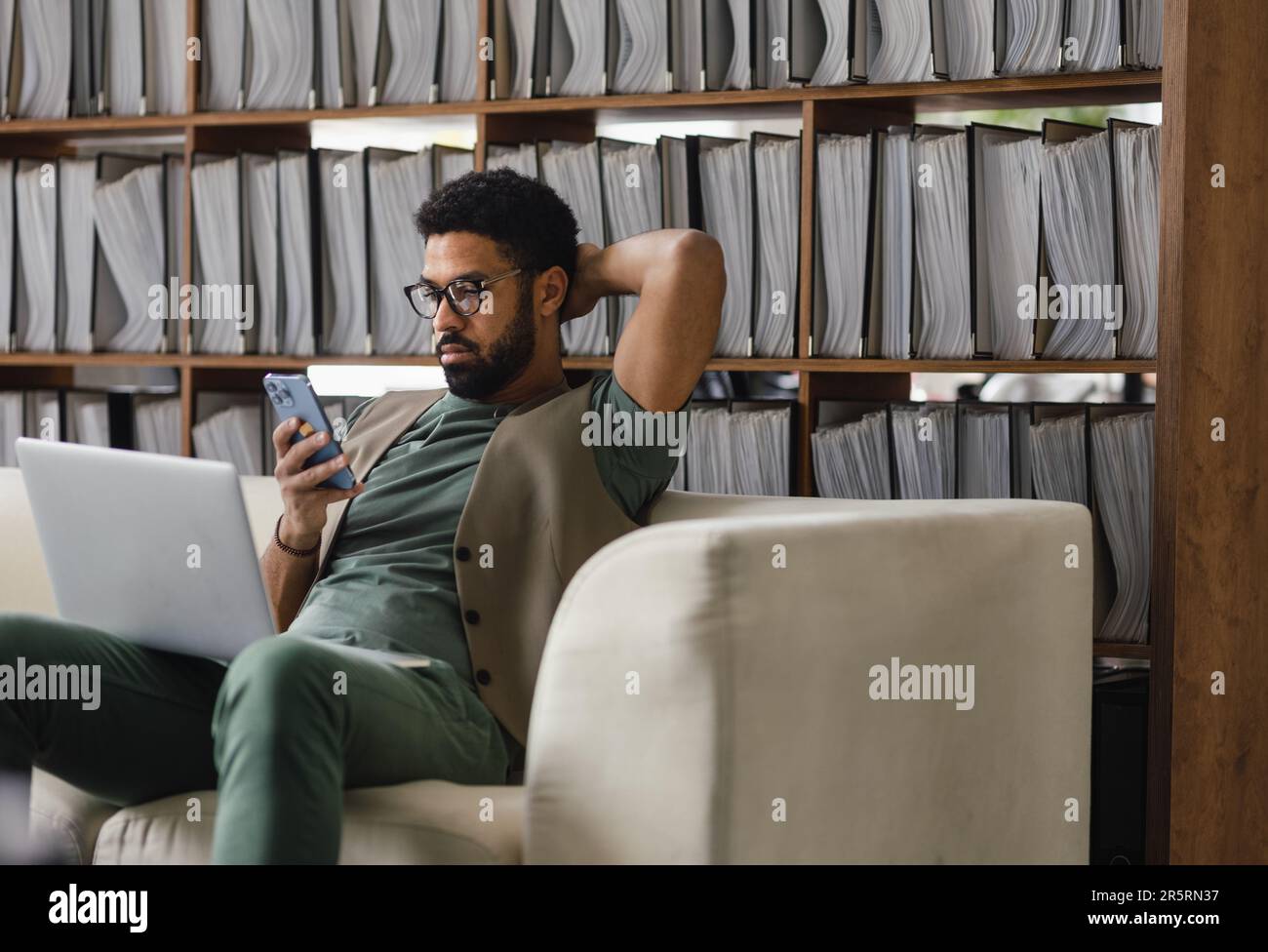 Young multiracial man sitting on sofa and working. Stock Photo