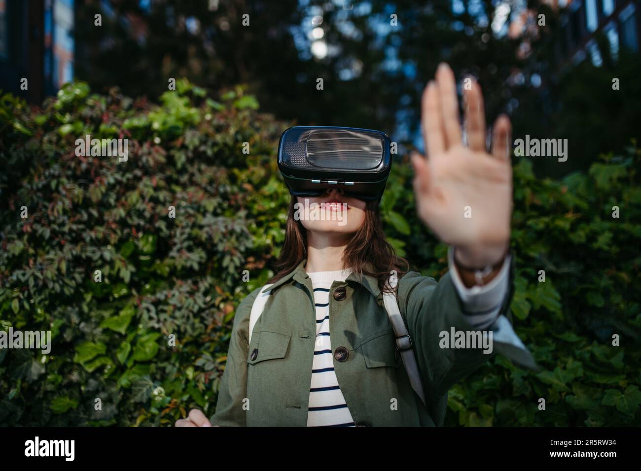 Portrait of young woman with virtual reality goggles outdoor. Stock Photo