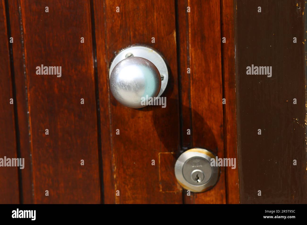 A vintage lock on an aged wooden door with a dark brown finish Stock Photo