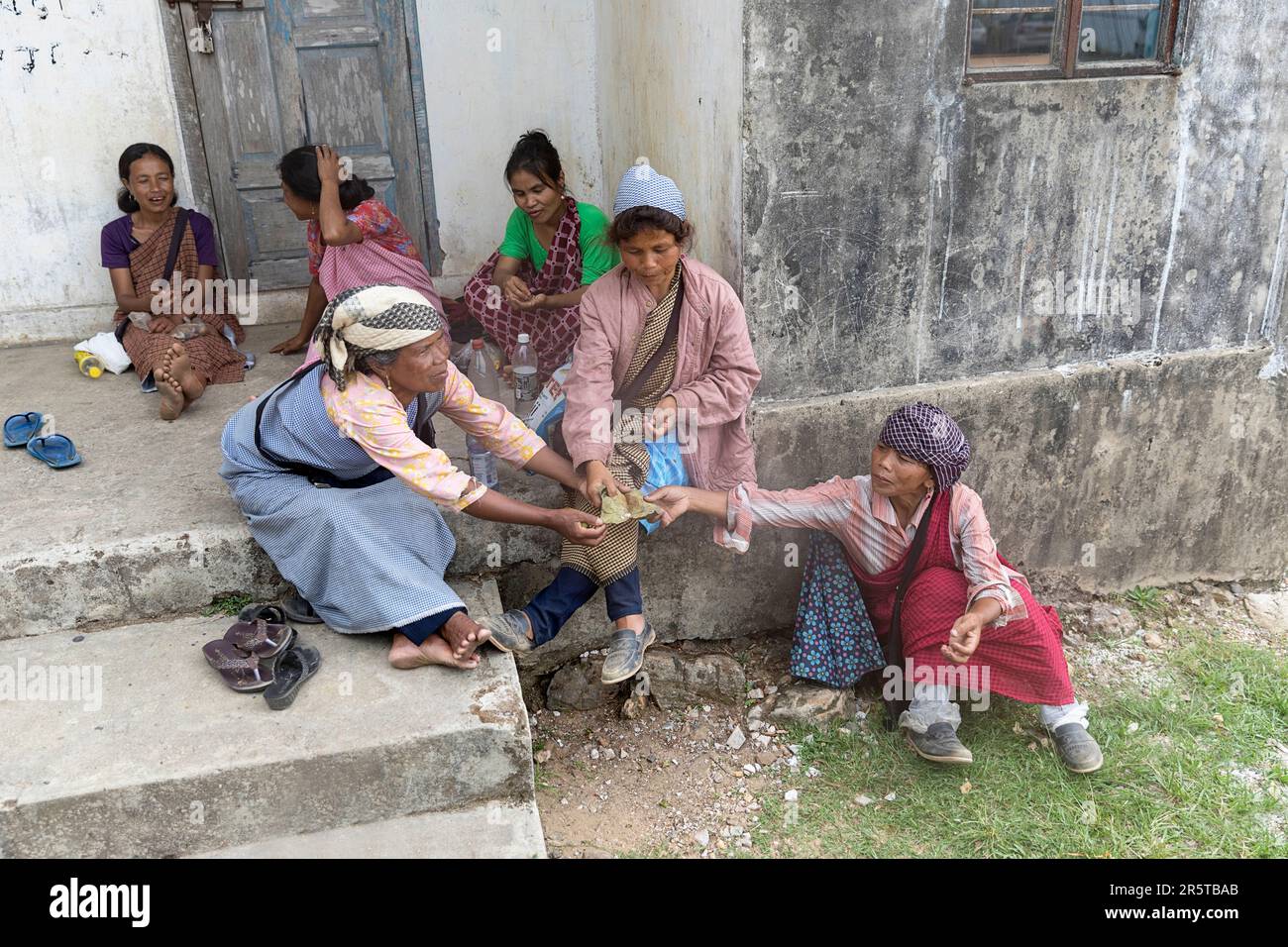 Ladies from Khasi tribe sitting infront of the entrance to the local house sharing betel nut for chewing in shillong region in meghalaya, india Stock Photo