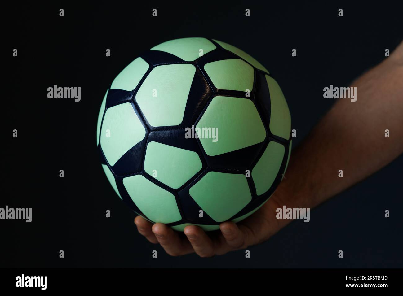 green black ball for handball in the athlete's hand on a black background Stock Photo