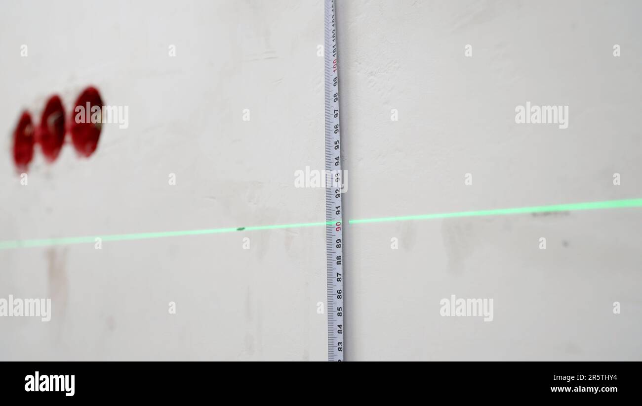 Measure the height with a laser level. Laser level and tape measure in action. A man uses a