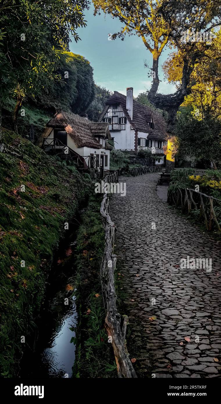 A scenic view of a stone paved path with rustic cottages. Queimadas Forest Park, Madeira. Stock Photo