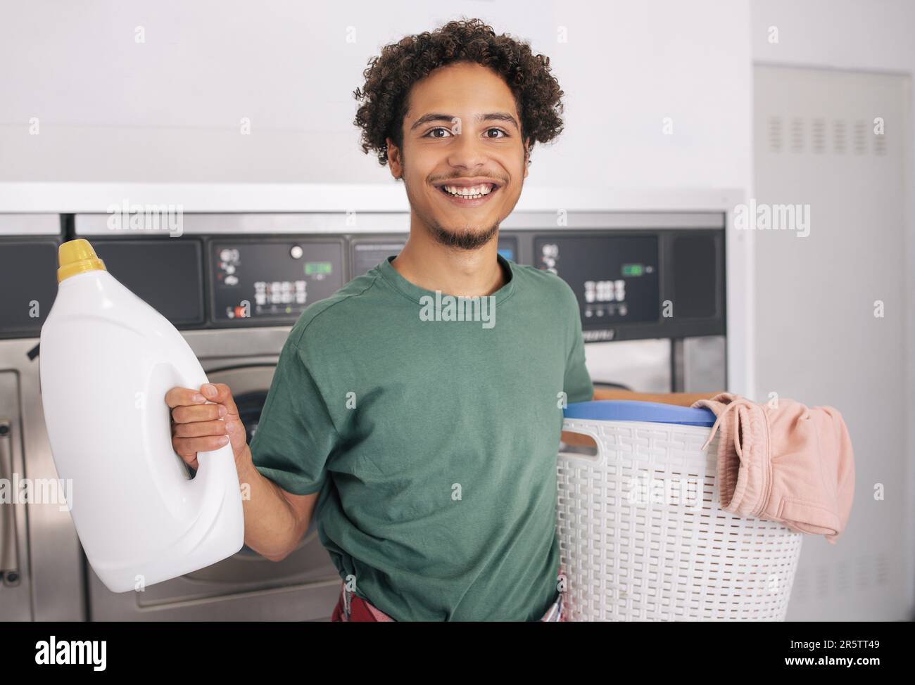 Happy Young Man Holding Basket With Clean Clothes At Laundry Stock ...