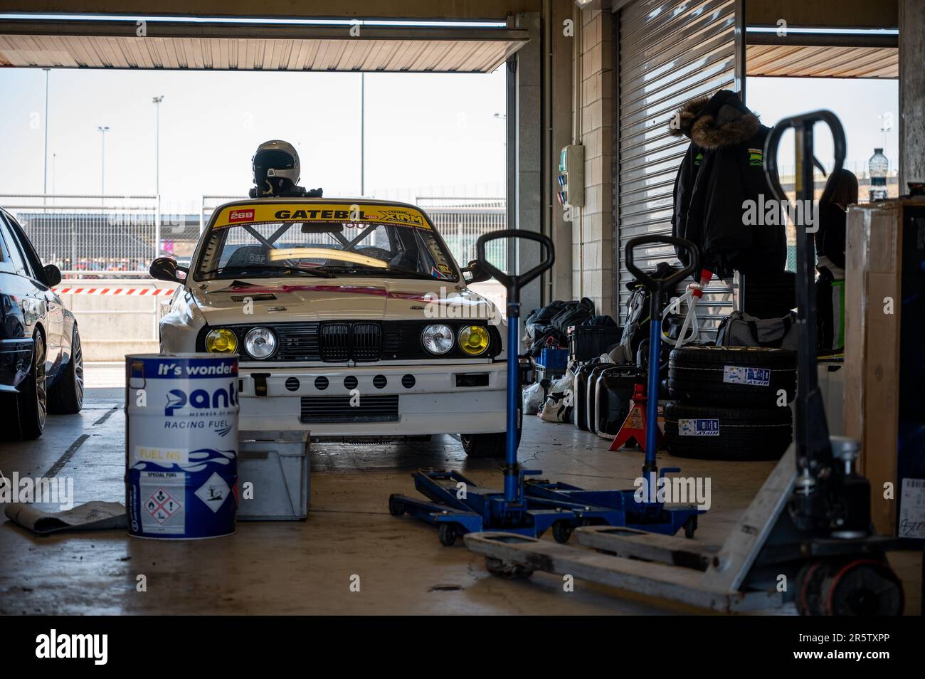 Detail of an old white BMW E30 in the pits while the driver and the ...