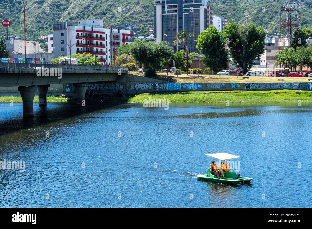 Two people enjoying a scenic boat ride, passing underneath a bridge over a tranquil lake Stock Photo