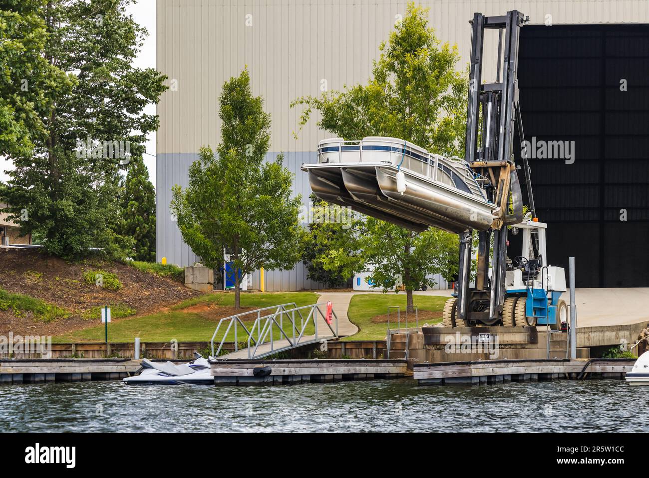 Pontoon boat removed from dry dock marina storage resting on fork lift