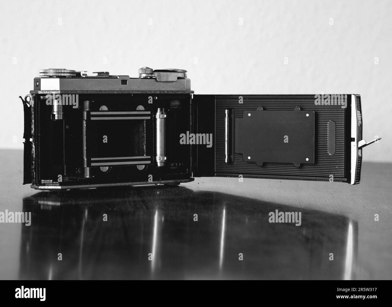 A grayscale shot of a vintage Kodak film camera on the table Stock Photo