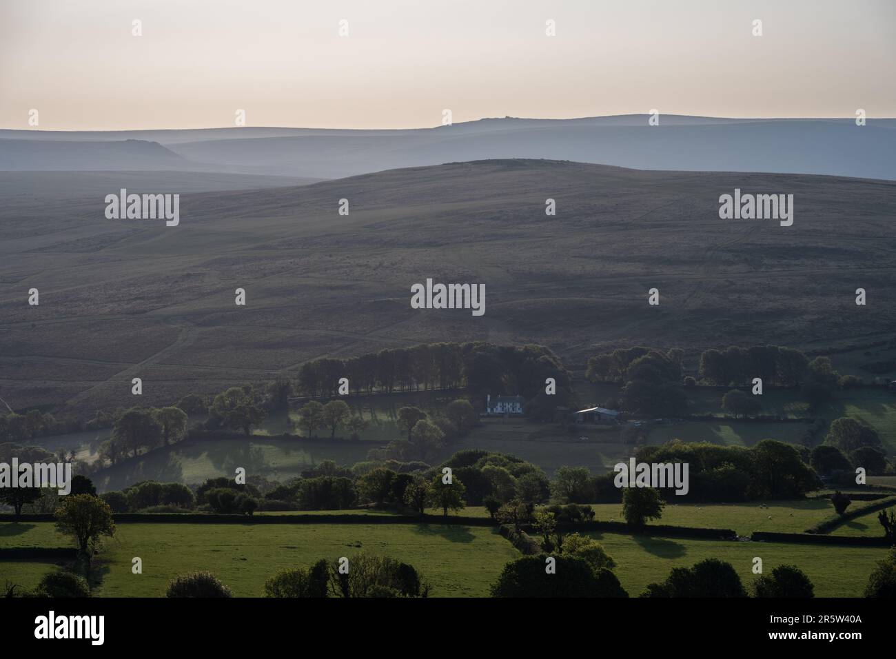 Morning light shines on Gibbet Hill and the distant hills of the Willsworthy Range in Dartmoor as seen from Brent Tor hill in West Devon. Stock Photo