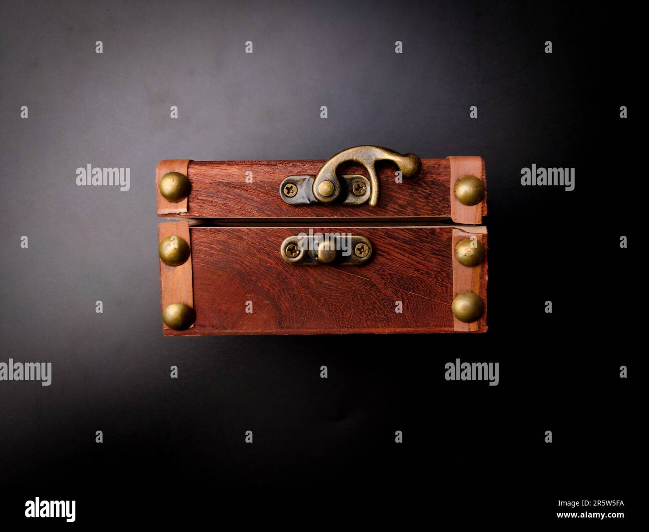 A vintage wooden chest featuring brass buttons on a black backdrop Stock Photo