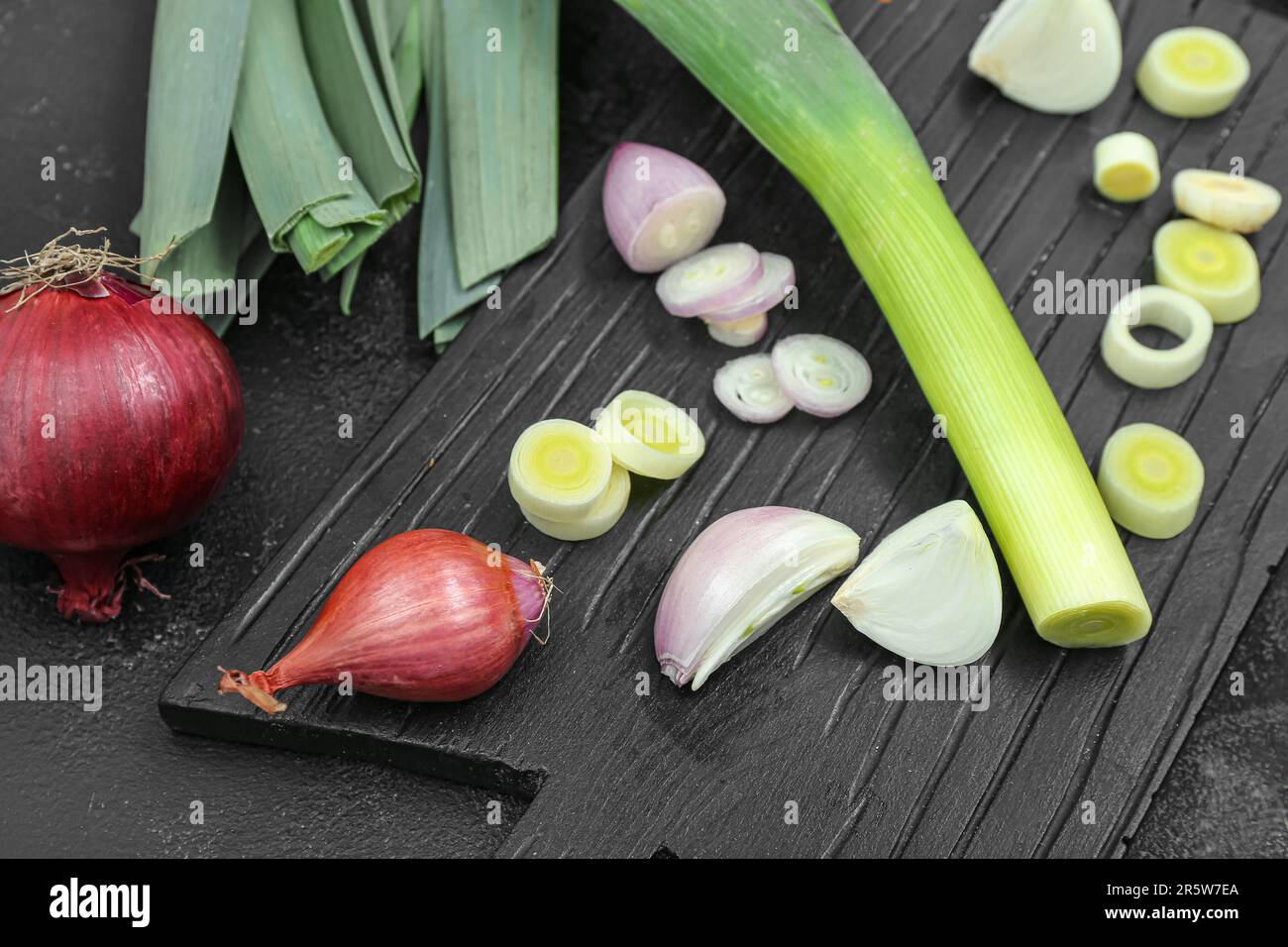 Board with different kinds of onion on grunge black background Stock ...