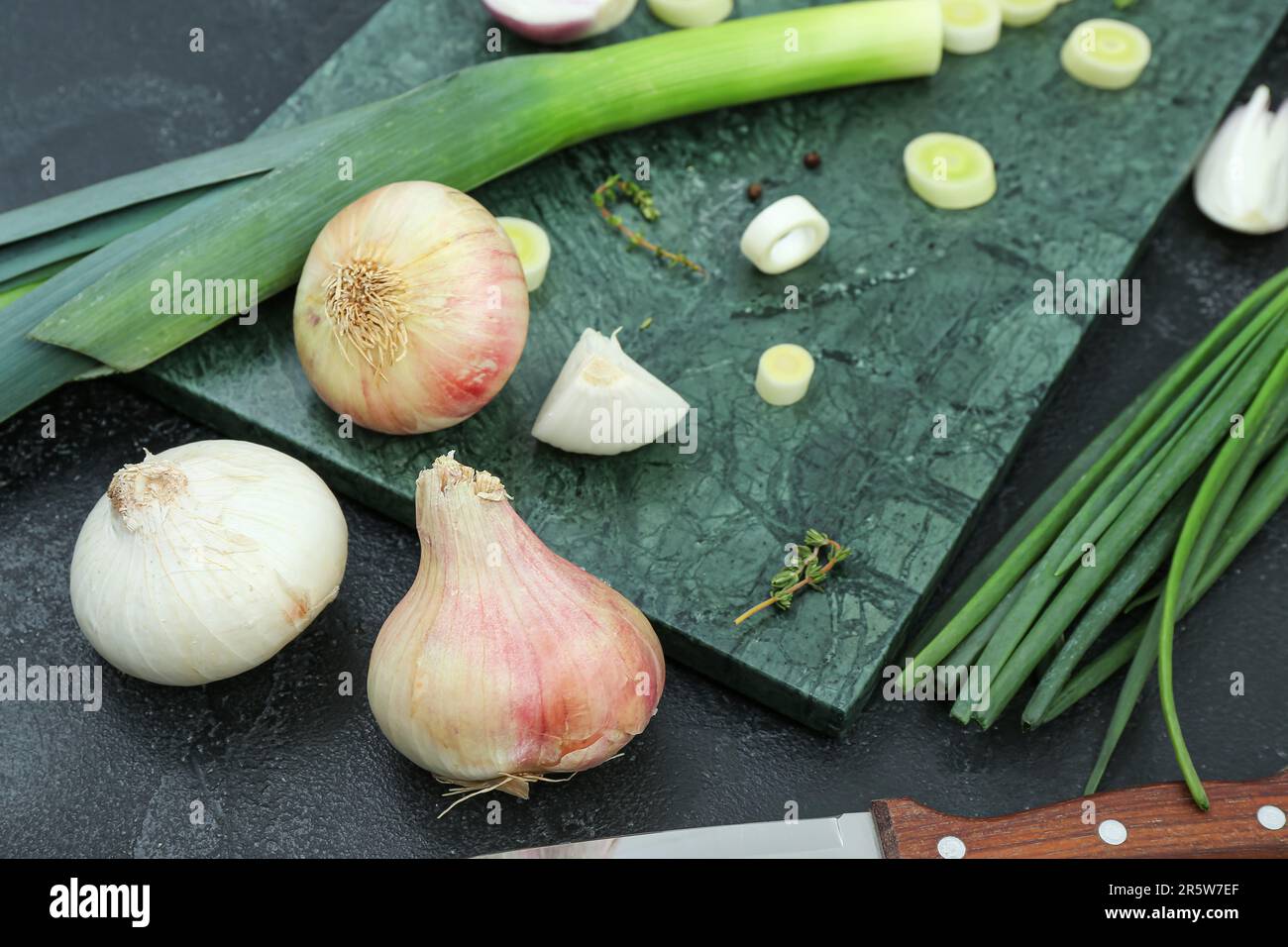 Board with different kinds of onion on grunge black background Stock ...