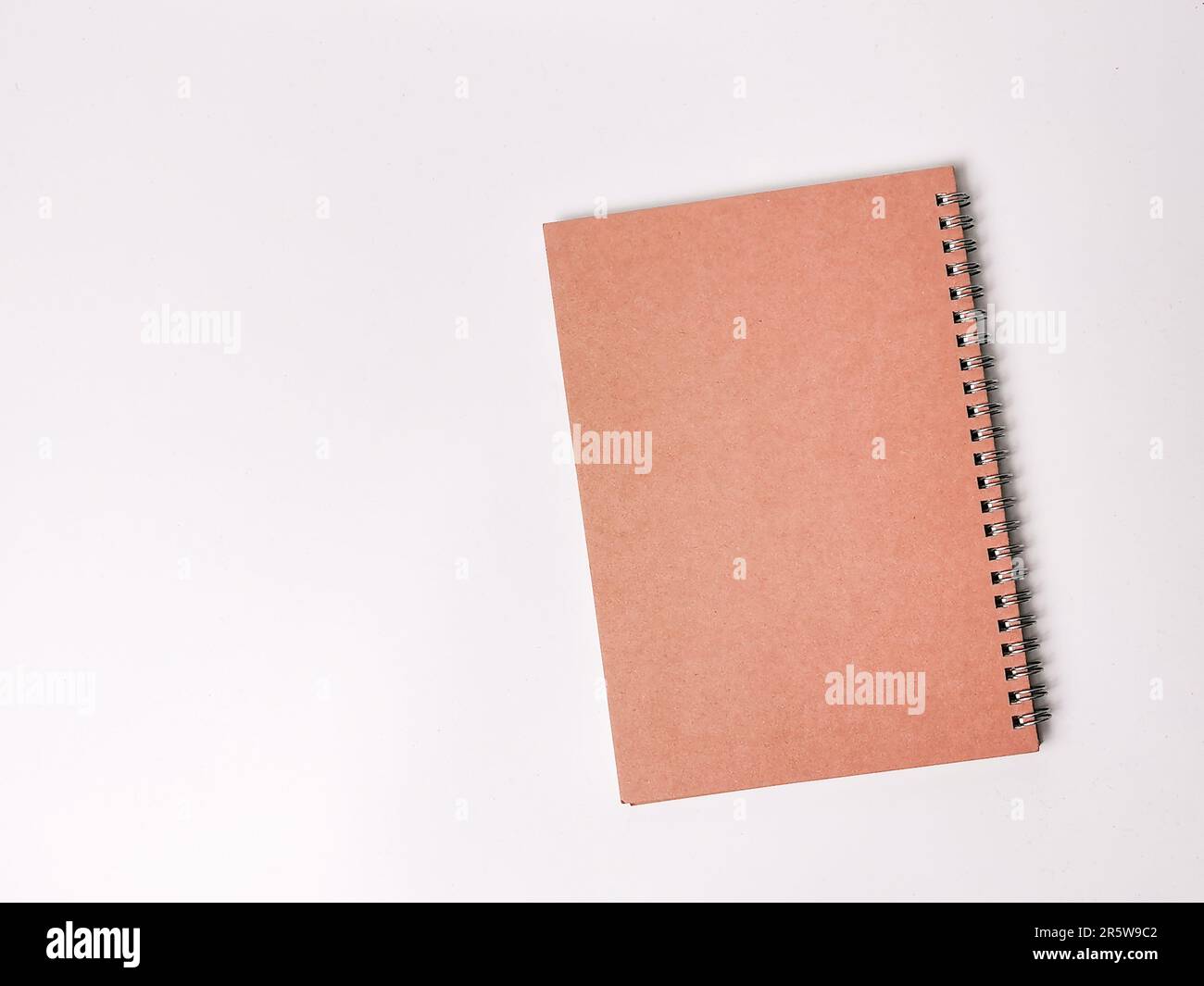A brown spiral notebook lying flat on a white surface. Stock Photo