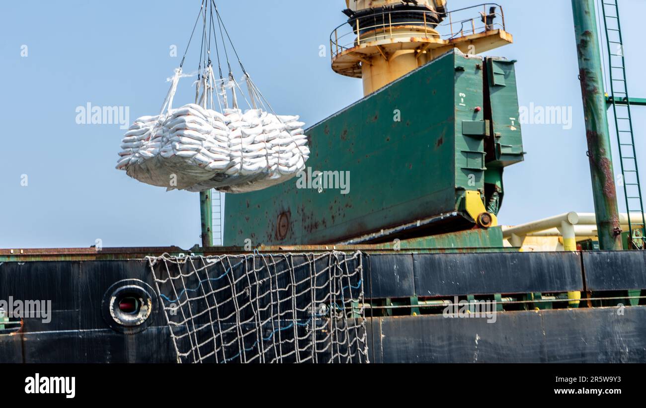 Crane loading sacks of raw material to an international ship for export