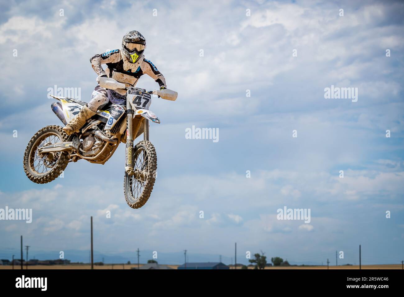 A male dirt biker is captured jumping his motorbike into the air, his body and bike silhouetted against the sky Stock Photo