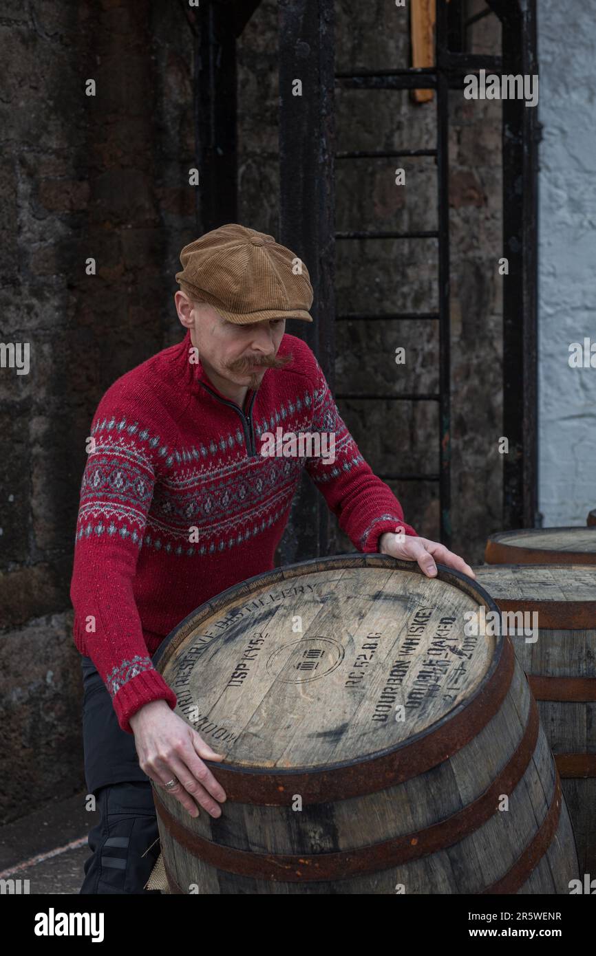 Worker rolling whisky cask in whisky distillery , Springbank , Scotland. Stock Photo