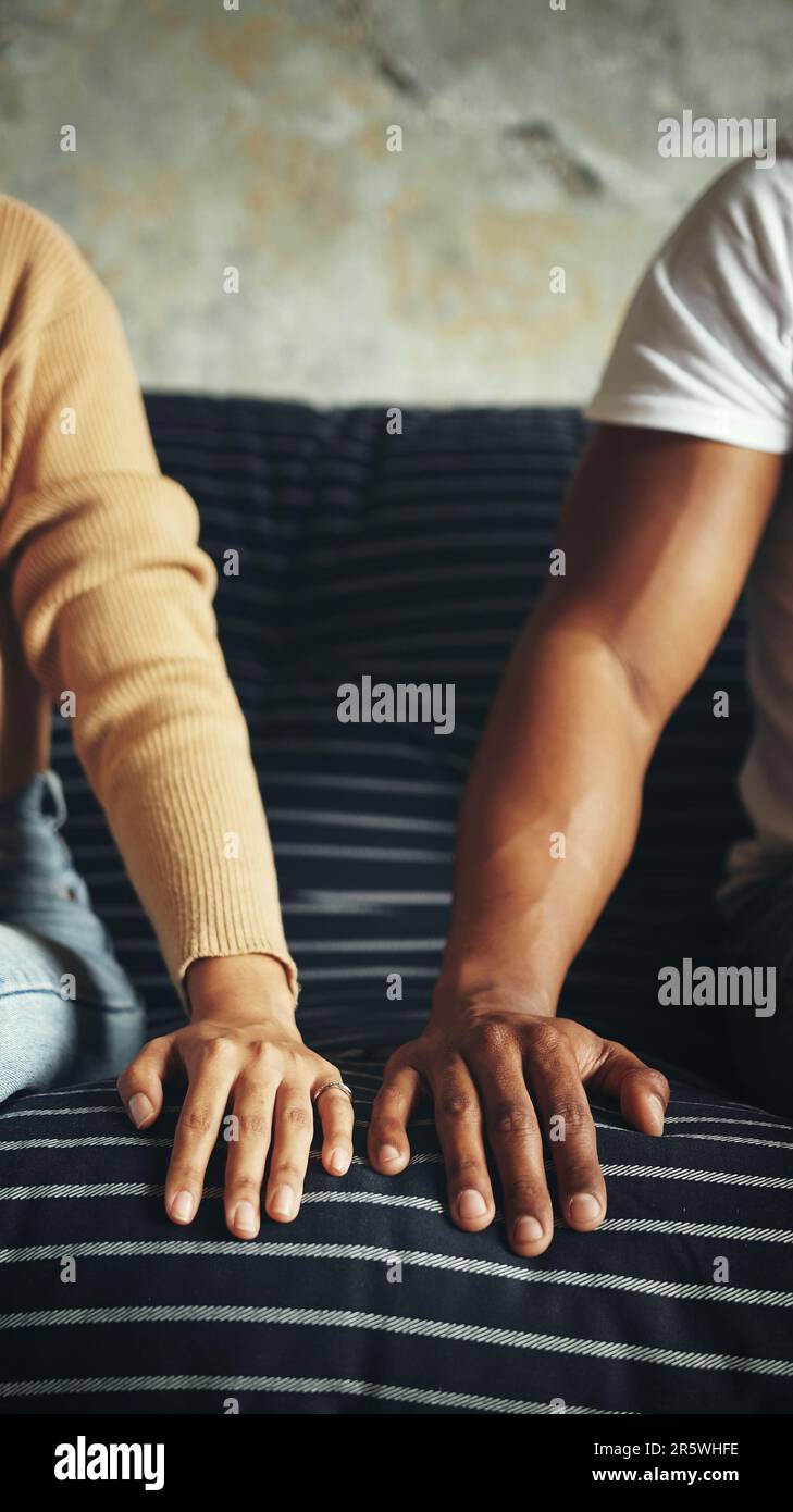 Trying to overcome the little distance between them. Closeup shot of an unrecognisable couple resting their hands alongside each other on a couch. Stock Photo