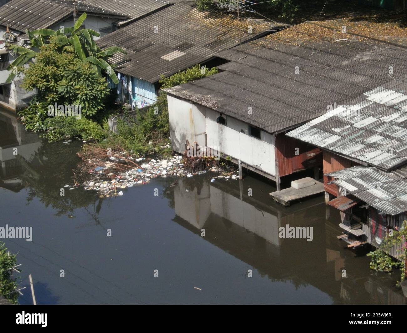 Bangkok, Thailand - August 22th 2010 : Slum on stilts on the river. They are unsanitary and represent a risk of disease. Stock Photo