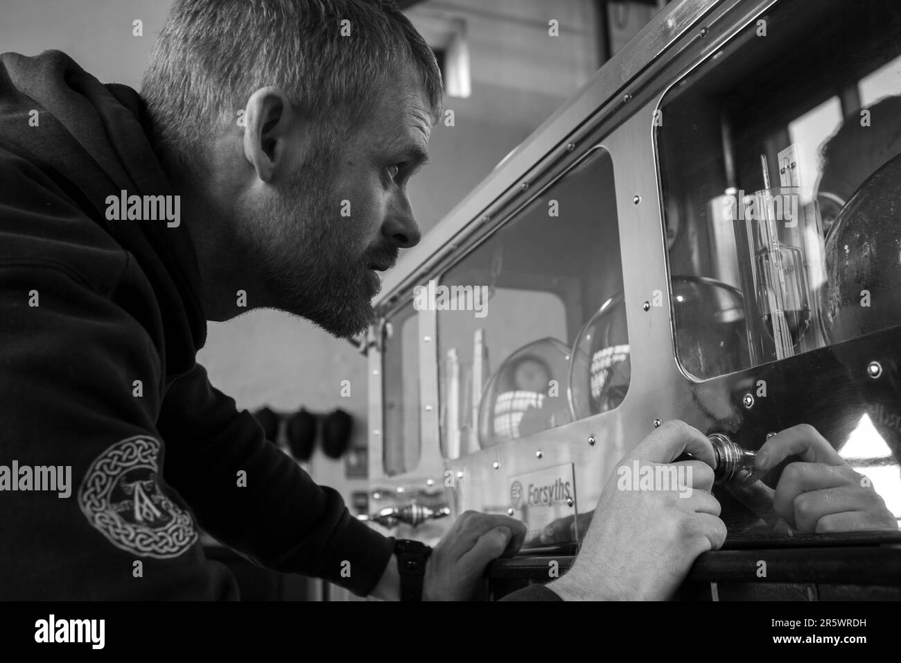 still man checks alcohol levels in the Spirit Safe at Ardbeg Distillery, Isle of Islay, Inner Hebrides, Scotland, United Kingdom Stock Photo