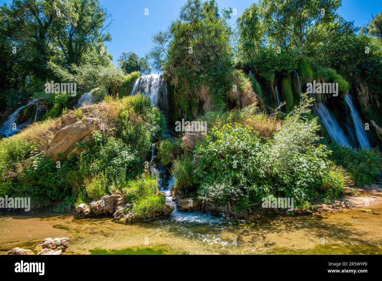 A majestic natural waterfall surrounded by lush greenery is showcased ...