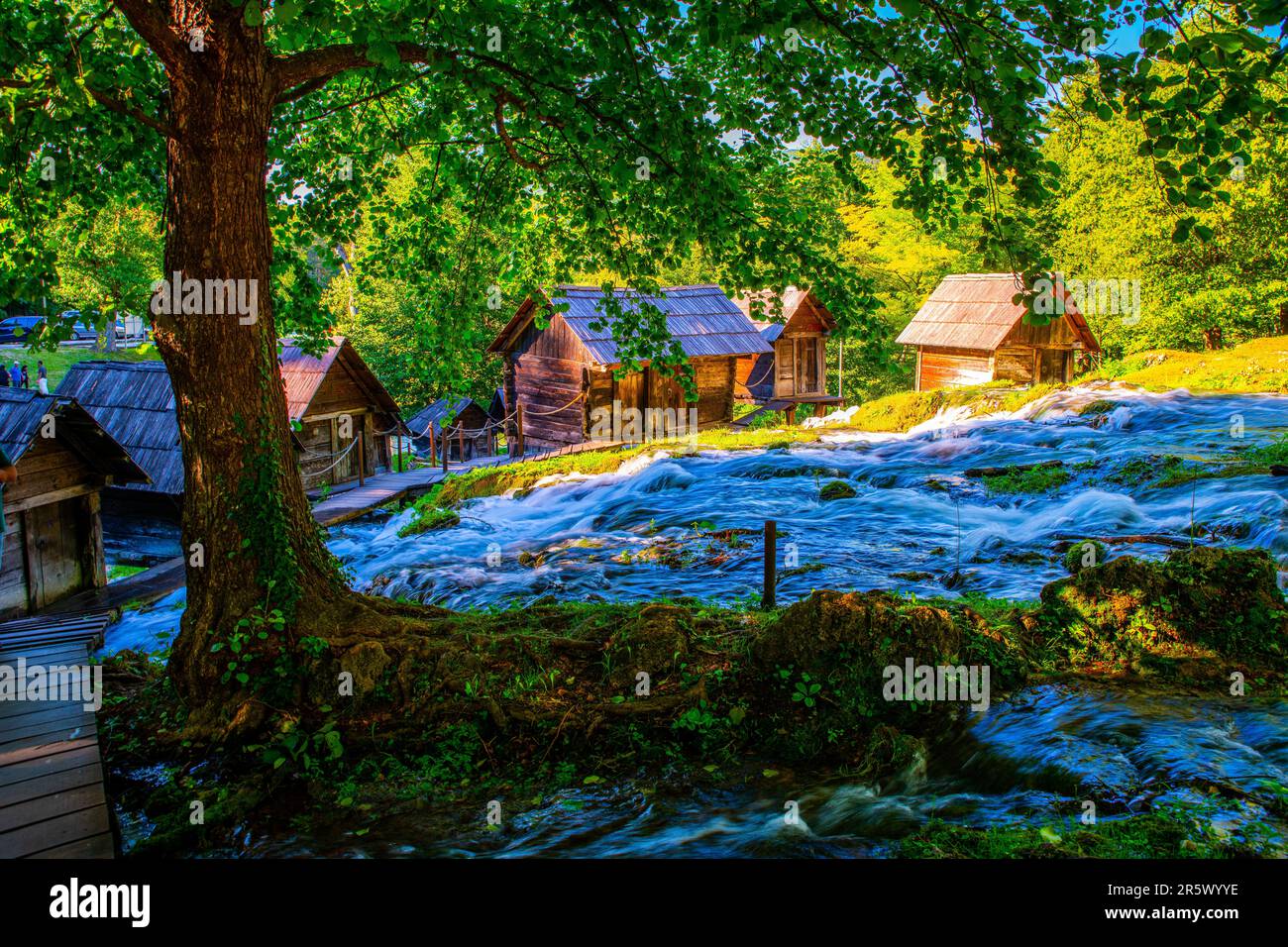 A picturesque outdoor river flowing alongside wooden cabins nestled in ...