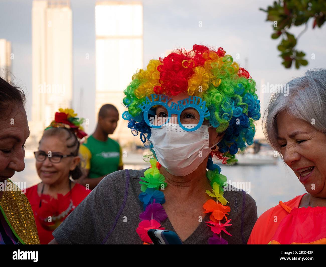 Cartagena, Cartagena Province, Bolivar, Colombia - February 17 2023: Colombian Woman Wearing a Colorful Wig and Light Blue Glasses that say 'Happy Bir Stock Photo