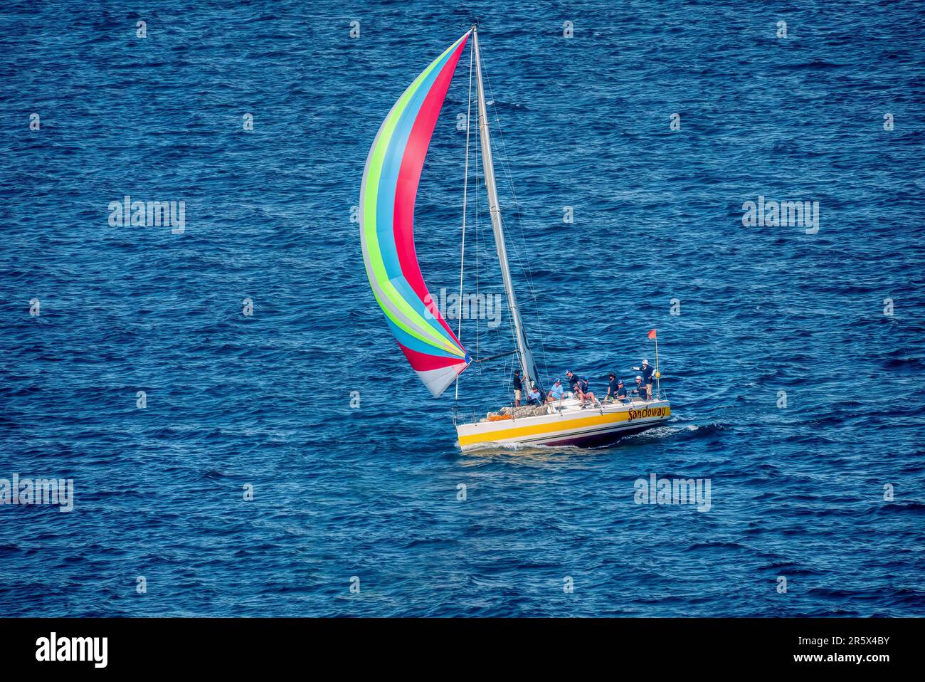 Puerto Galera, Philippines - March 30, 2013. A yacht sailing downwind in a local regatta, with its colorful spinnaker flying and crew on deck. Stock Photo