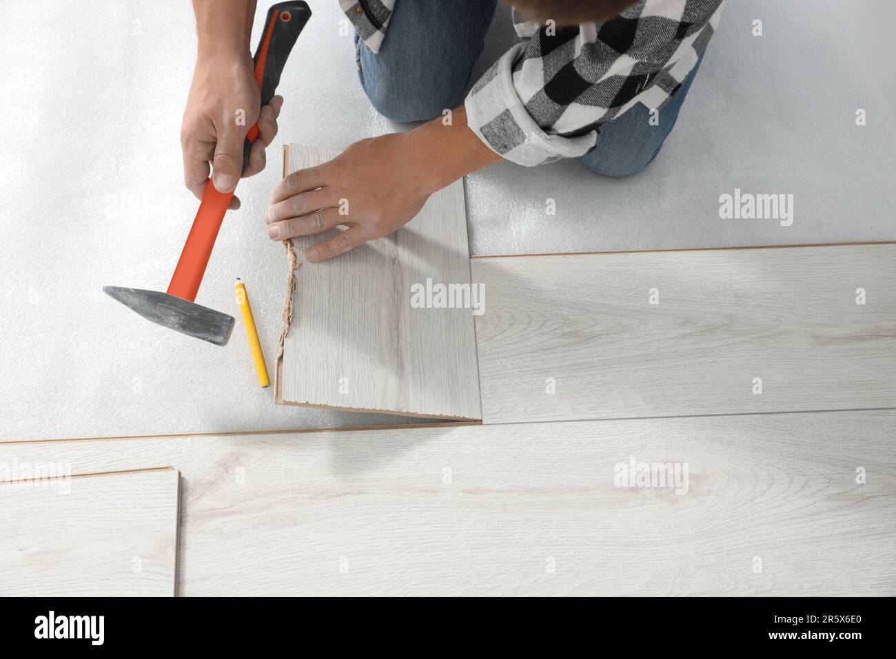 Professional worker using hammer during installation of new laminate ...