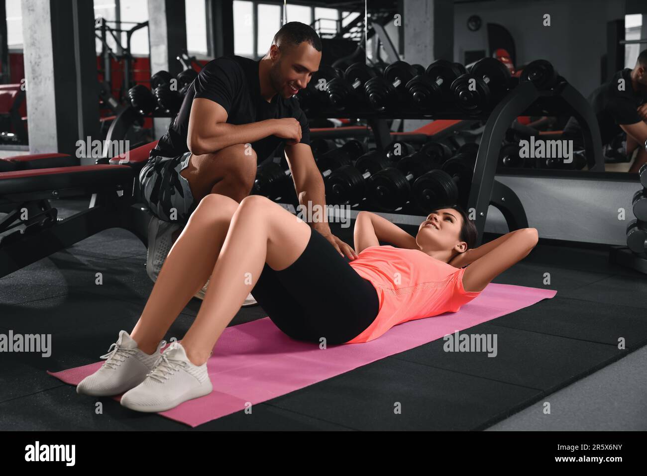 Trainer explaining woman how to do exercise properly in modern gym ...
