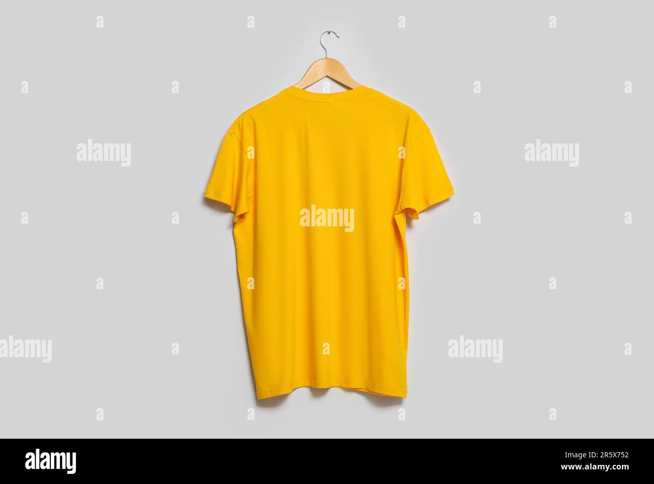 https://c8.alamy.com/comp/2R5X752/hanger-with-yellow-t-shirt-on-light-wall-mockup-for-design-2R5X752.jpg