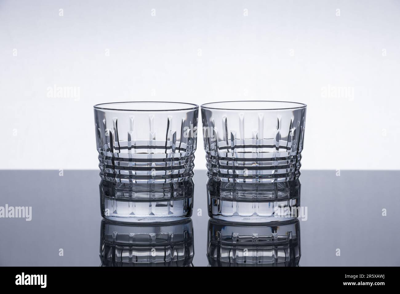 Crystal whiskey glasses on a reflective surface. Isolated object