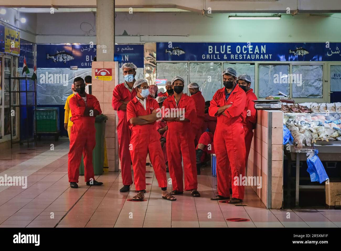 Professional fish cleaners team with red uniform on fish market Al Mina. Group portrait of fish market staff.  Stock Photo