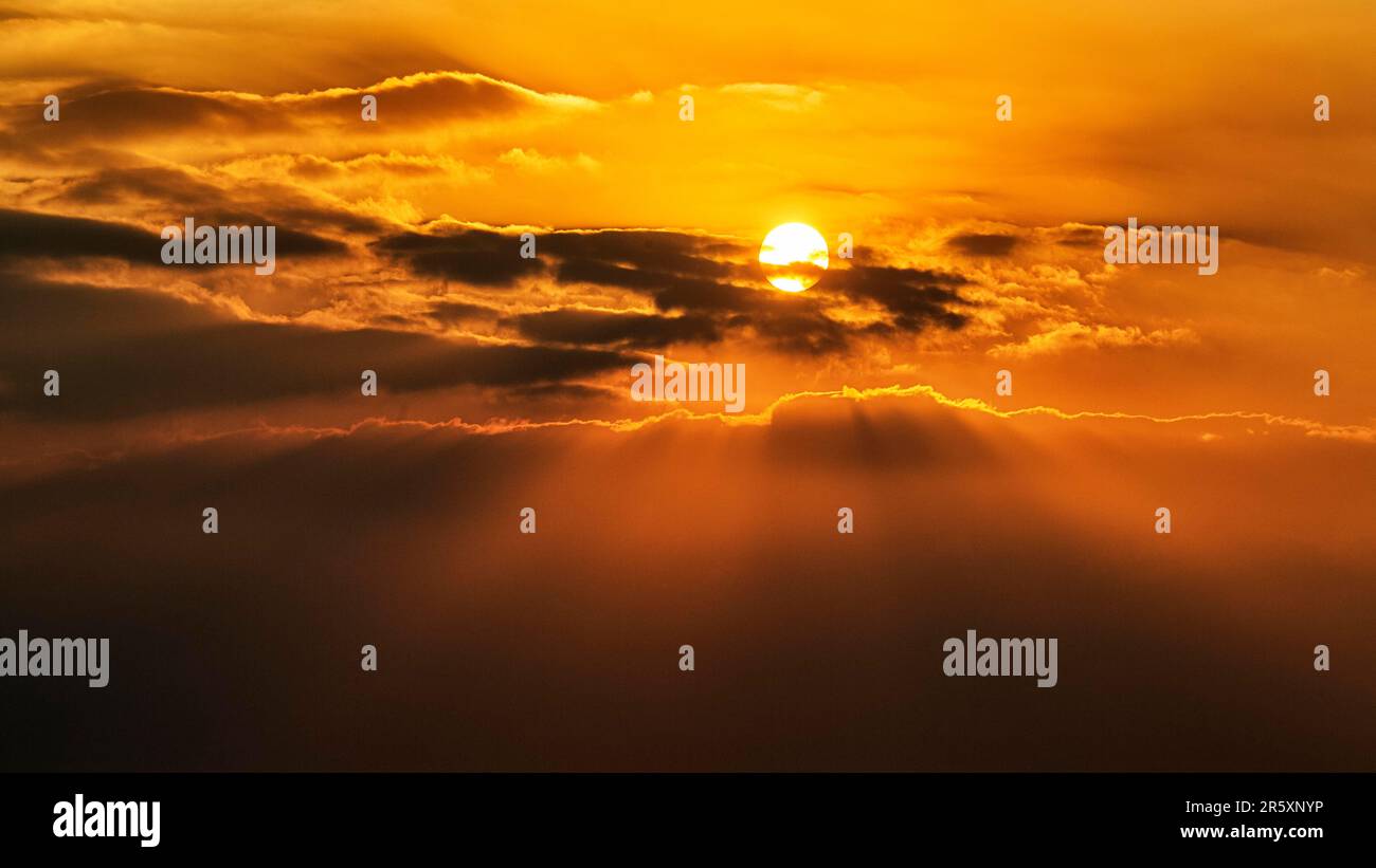 Sun shining through clouds, sun rays in the evening sky, full-frame ...