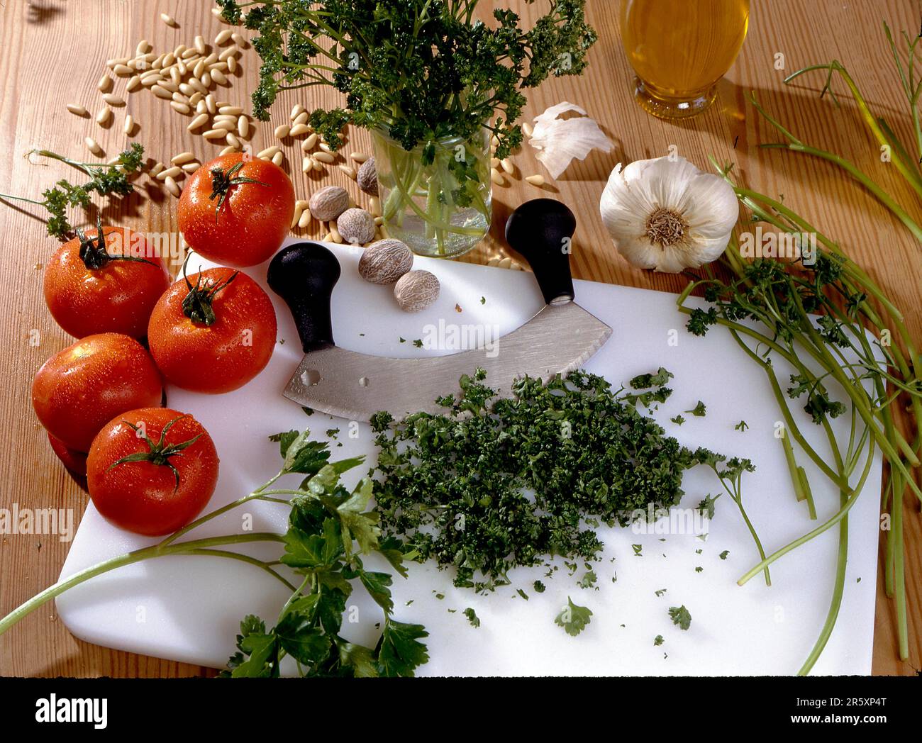 Chopping board, chopping knife Oregano, basil (Ocimum basilicum), tomatoes, onions, pepper seeds, nutmeg Basil Stock Photo