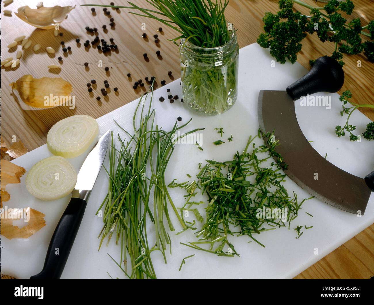 Chives and onions, peppercorns, chopping board, chopping knife Stock Photo