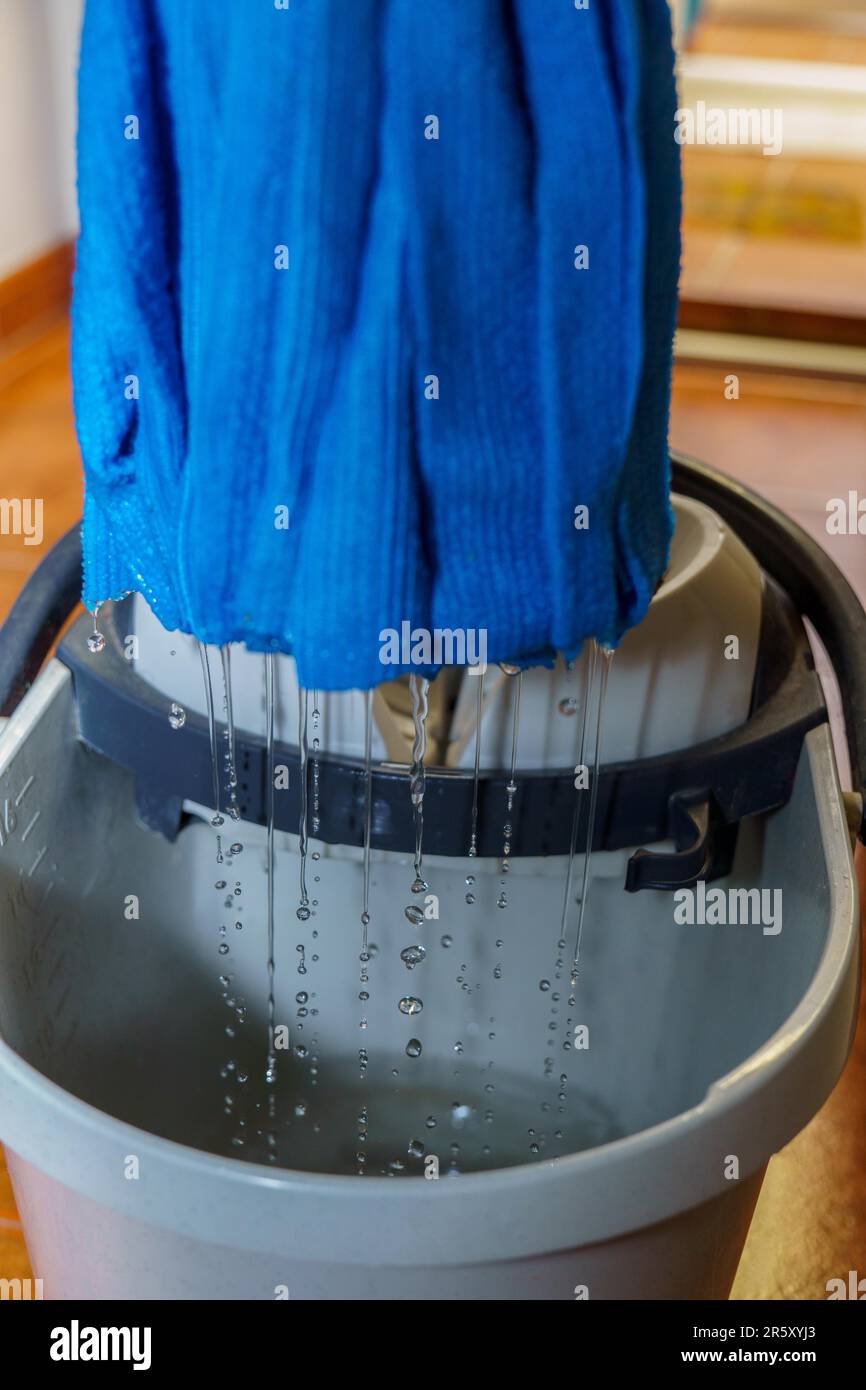 Closeup of a blue mop dripping drops of water into its bucket Stock