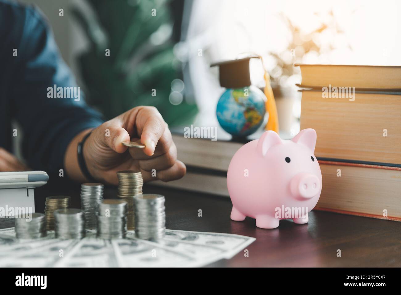 Hand putting coin on stack with piggy bank. Concept of saving money for a scholarship to study abroad at a university level. Financial planning accoun Stock Photo