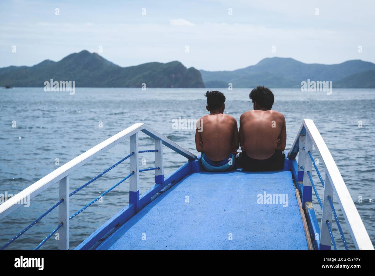 Palawan, Philippines - 28 February 2023: two men sitting at the bow of the boat to relax and enjoy the landscape Stock Photo