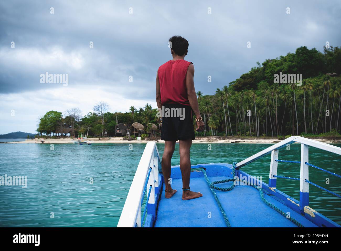 El Nido bay, Palawan, Philippines - 2 March 2023: Man viewing bamboo hut resort at the white beach island with turquoise water Stock Photo
