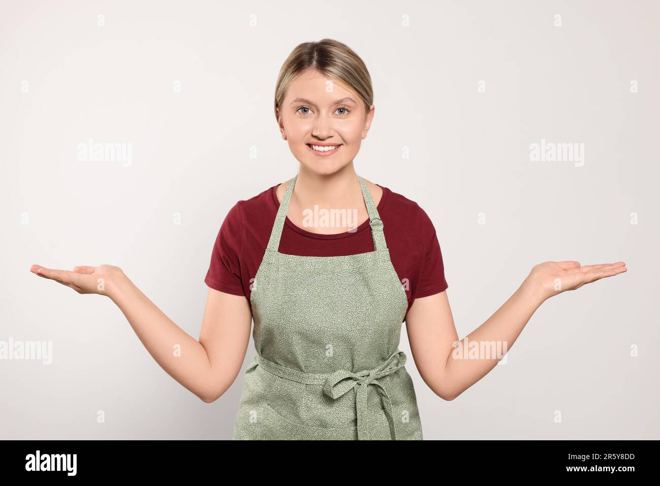 Beautiful young woman in clean apron on light grey background Stock ...
