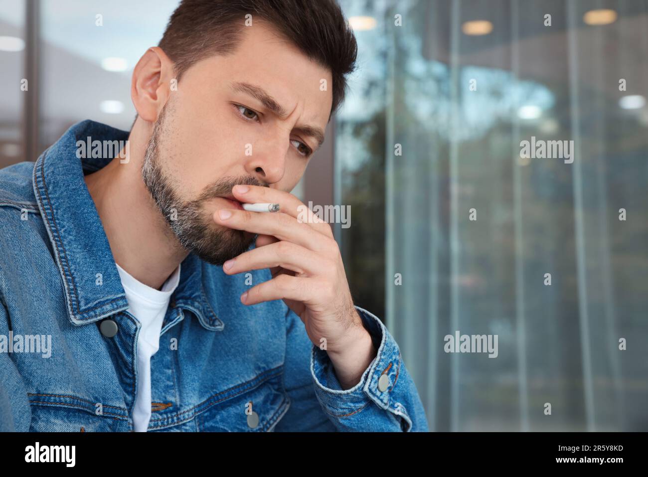 Handsome man smoking cigarette outdoors. Space for text Stock Photo