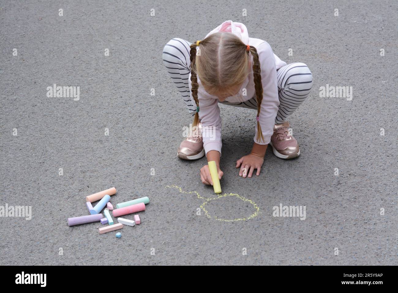 Little child drawing sun with chalk on asphalt Stock Photo - Alamy