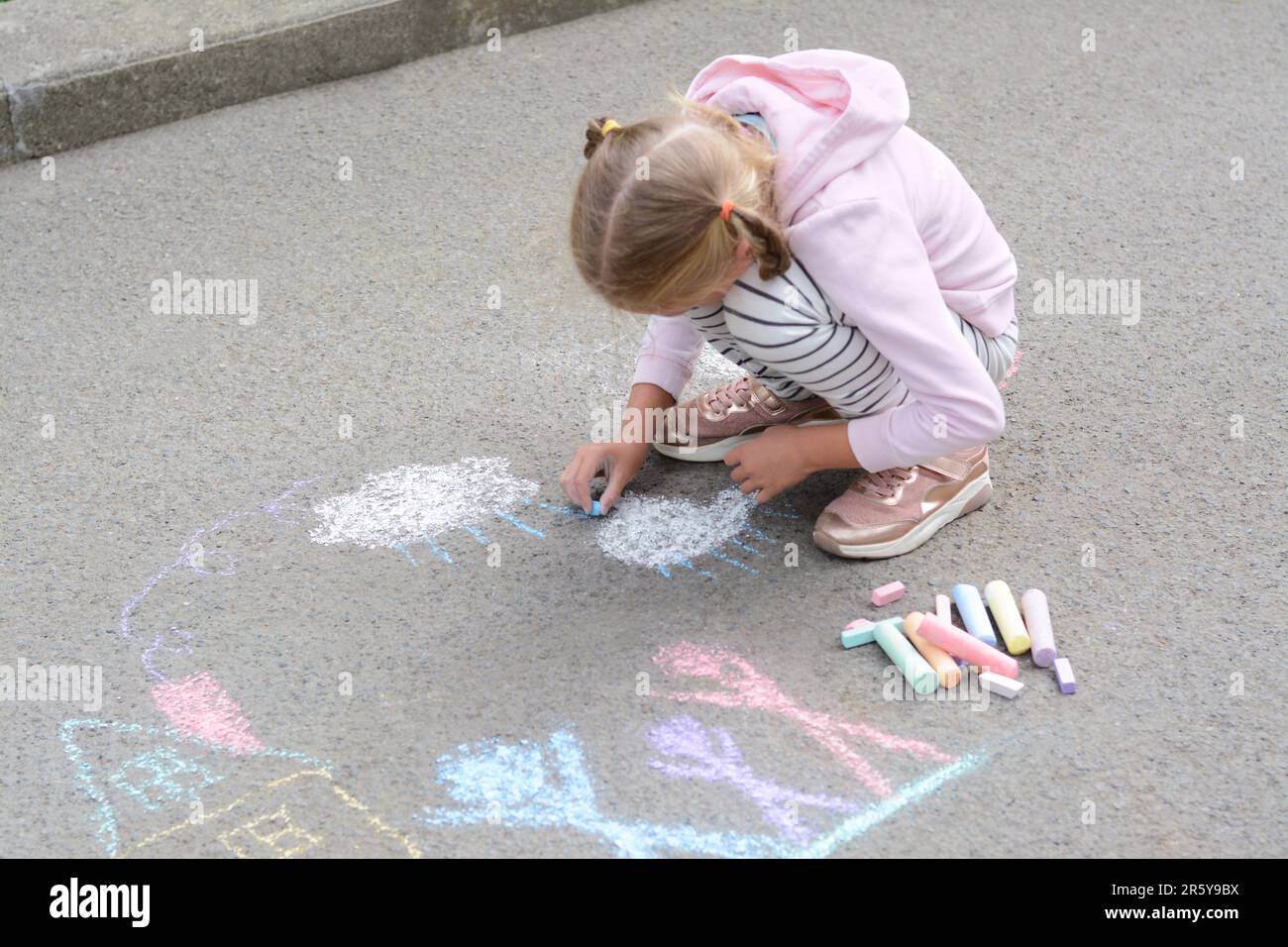 Little child drawing white clouds with chalk on asphalt Stock Photo - Alamy